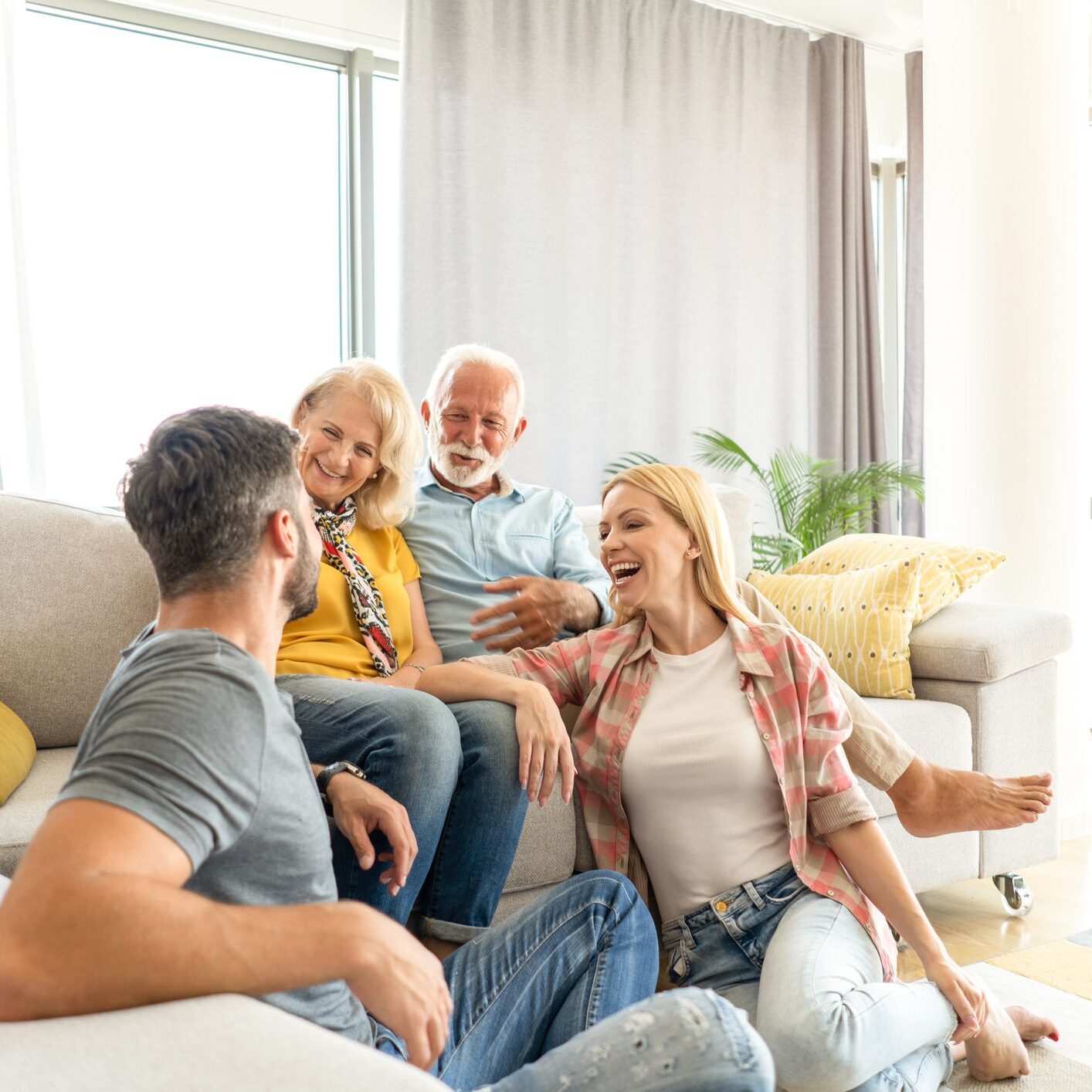 Happy adult children relaxing with parents at home.