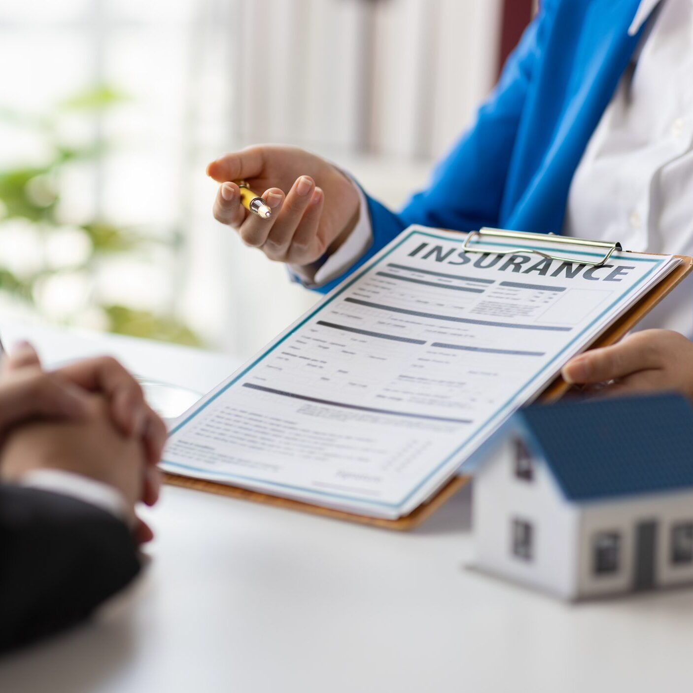 Insurance agent is explaining the terms of a home insurance contract document. Real estate agent discussing property insurance.